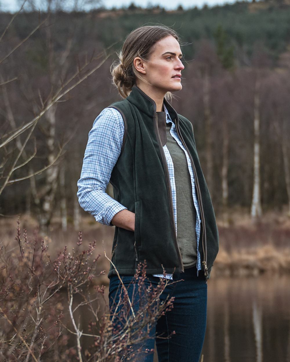 Pine Green Coloured Hoggs of Fife Stenton Ladies Fleece Gilet on forest background #colour_pine-green