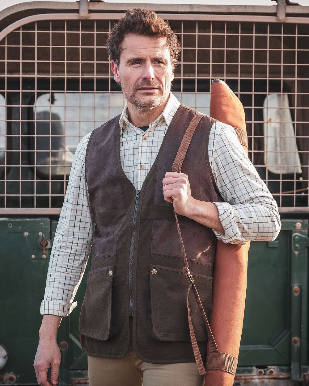 Dark Green coloured Hoggs of Fife Struther Shooting Vest on jeep background #colour_dark-green
