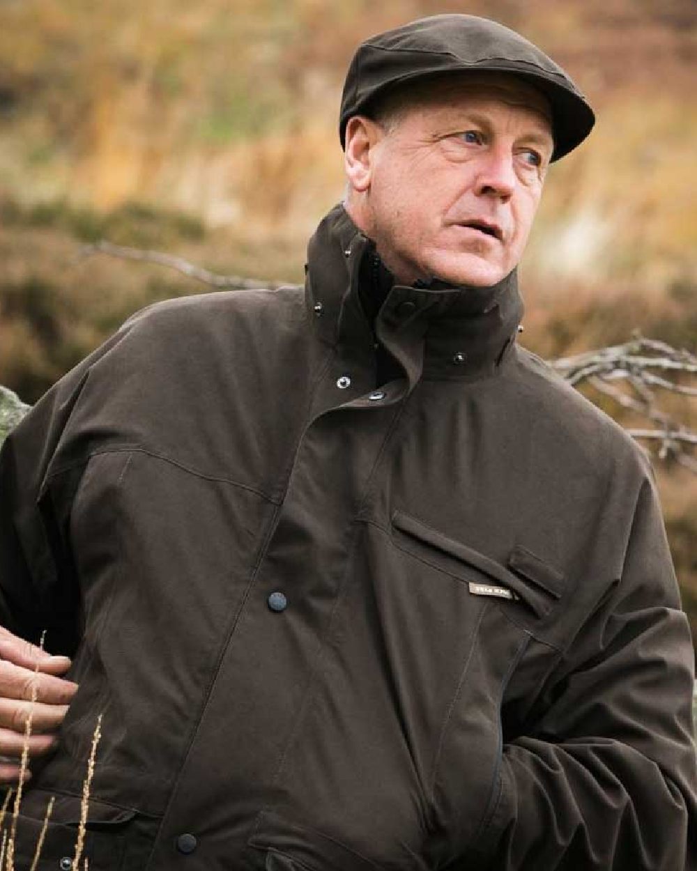 Olive coloured Jack Pyke Ashcombe Flat Cap on blurry background #colour_olive