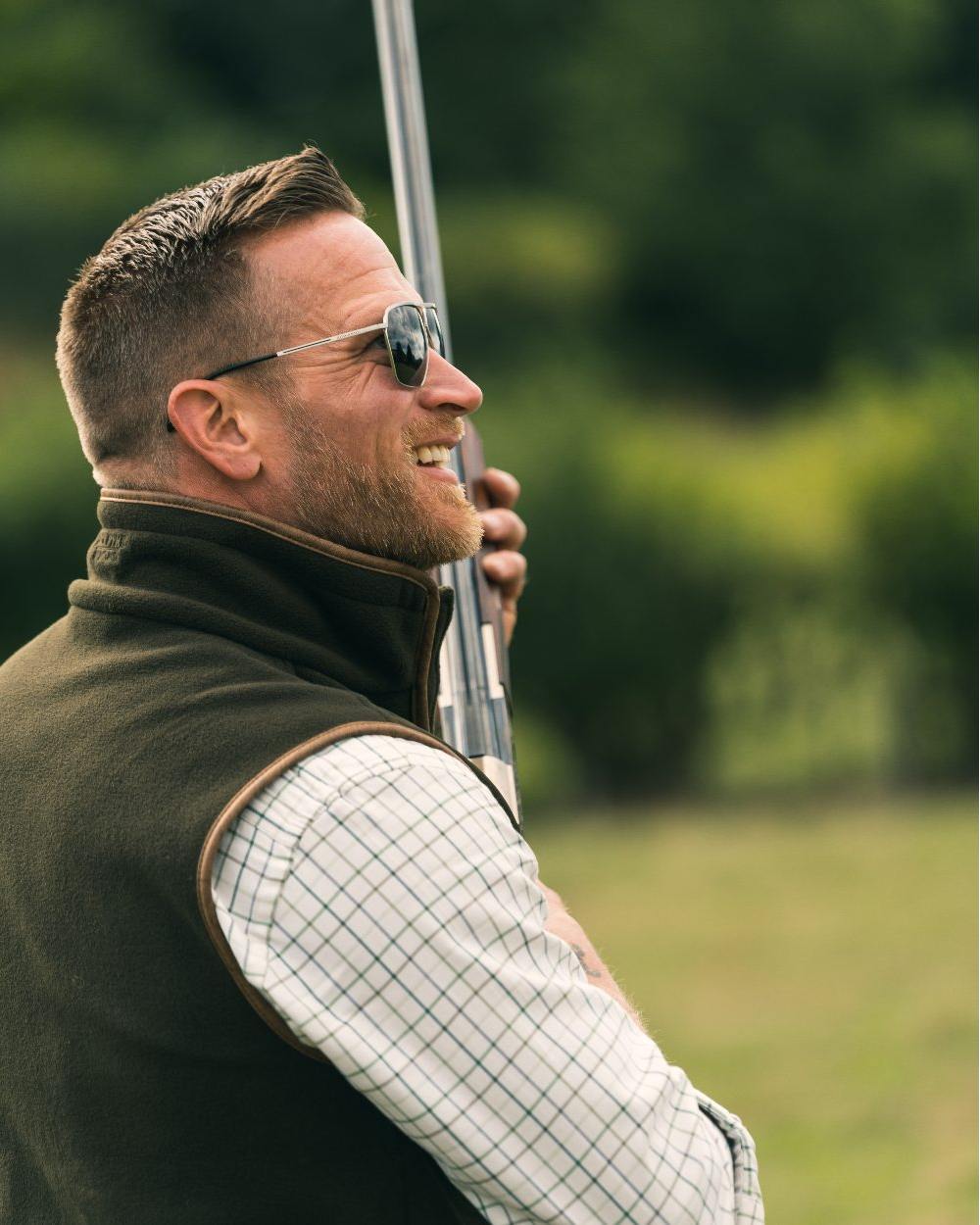 Dark Olive coloured Jack Pyke Countryman Fleece Gilet on blurry background #colour_dark-olive