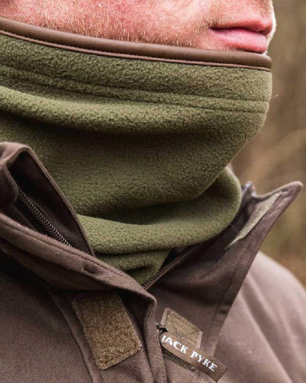 Light Olive coloured Jack Pyke Countryman Fleece Neck Gaiter on blurry background #colour_light-olive