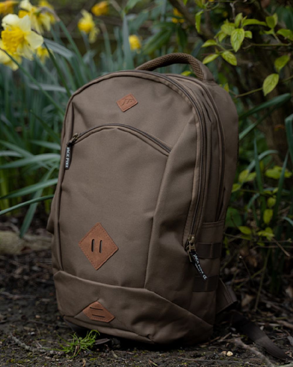 Olive Brown Jack Pyke Kestrel Rucksack on garden background #colour_olive-brown