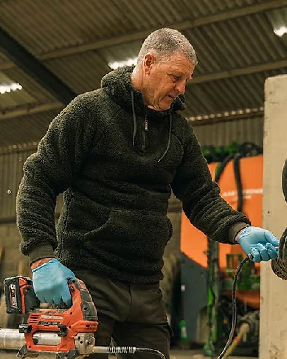 Dark Olive coloured Jack Pyke Sherpa Fleece Hoodie on factory background #colour_dark-olive