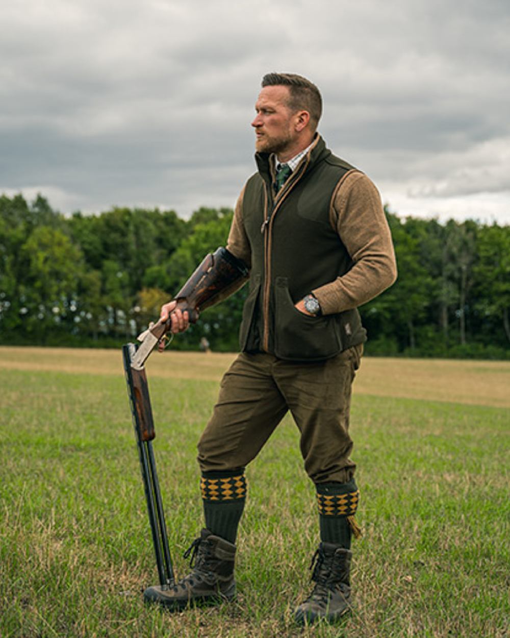 Dark Olive Jack Pyke Shooters Gilet on forest background #colour_dark-olive