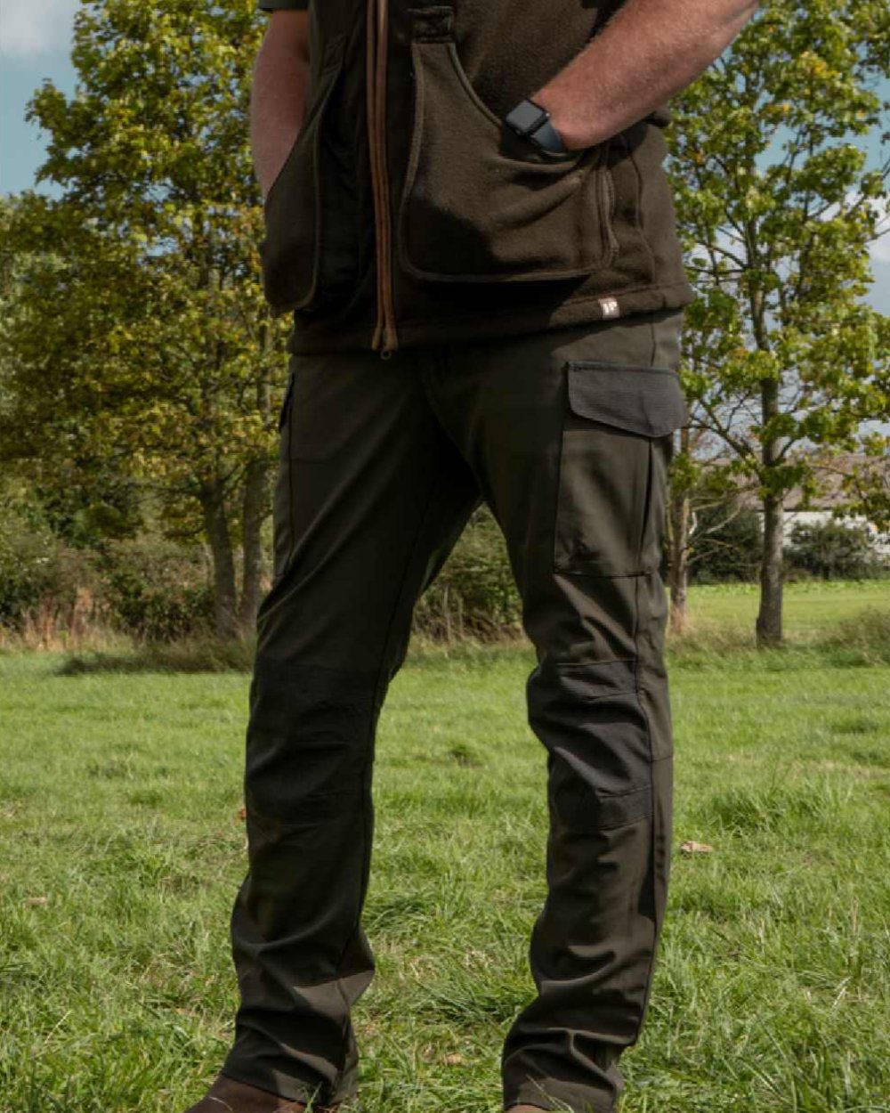 Green coloured Jack Pyke Softshell Trousers on grass background #colour_green