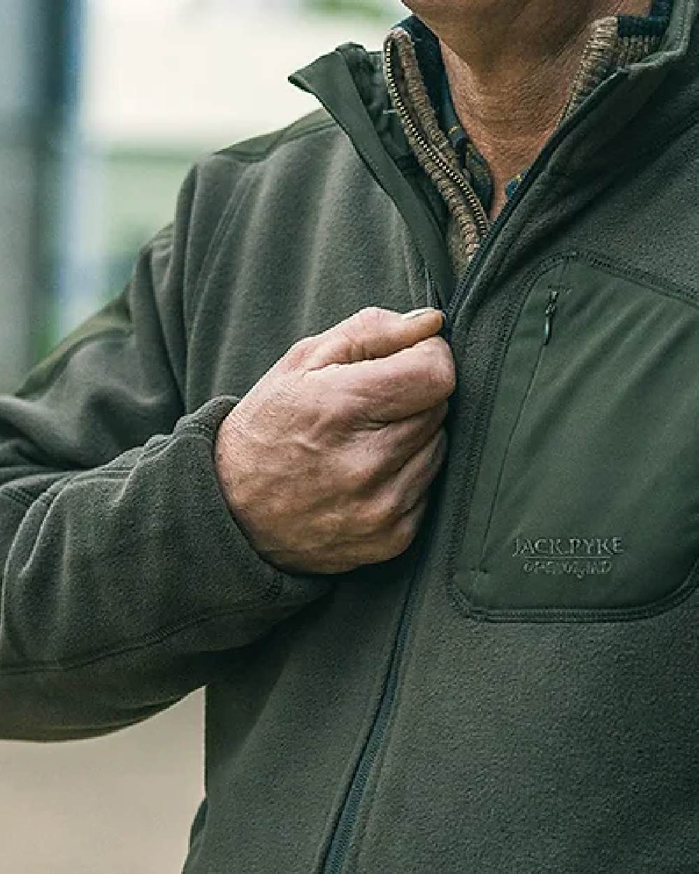 Green coloured Jack Pyke Weardale Fleece Jacket on blurry background #colour_green