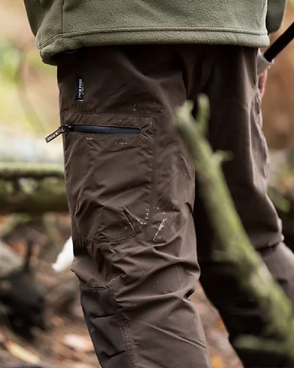Brown coloured Jack Pyke Weardale Hunting Trousers on forest background #colour_brown