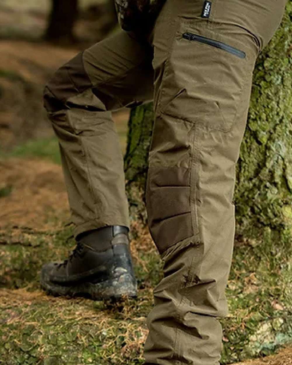 Green coloured Jack Pyke Weardale Hunting Trousers on forest background #colour_green