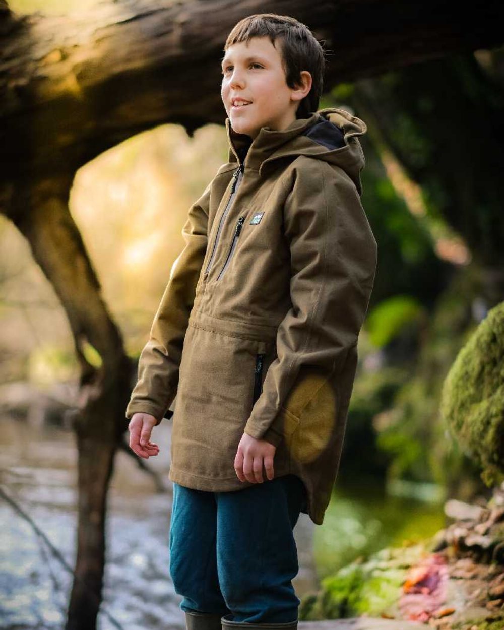 Teak coloured Ridgeline Kids Monsoon Smock on forest background #colour_teak