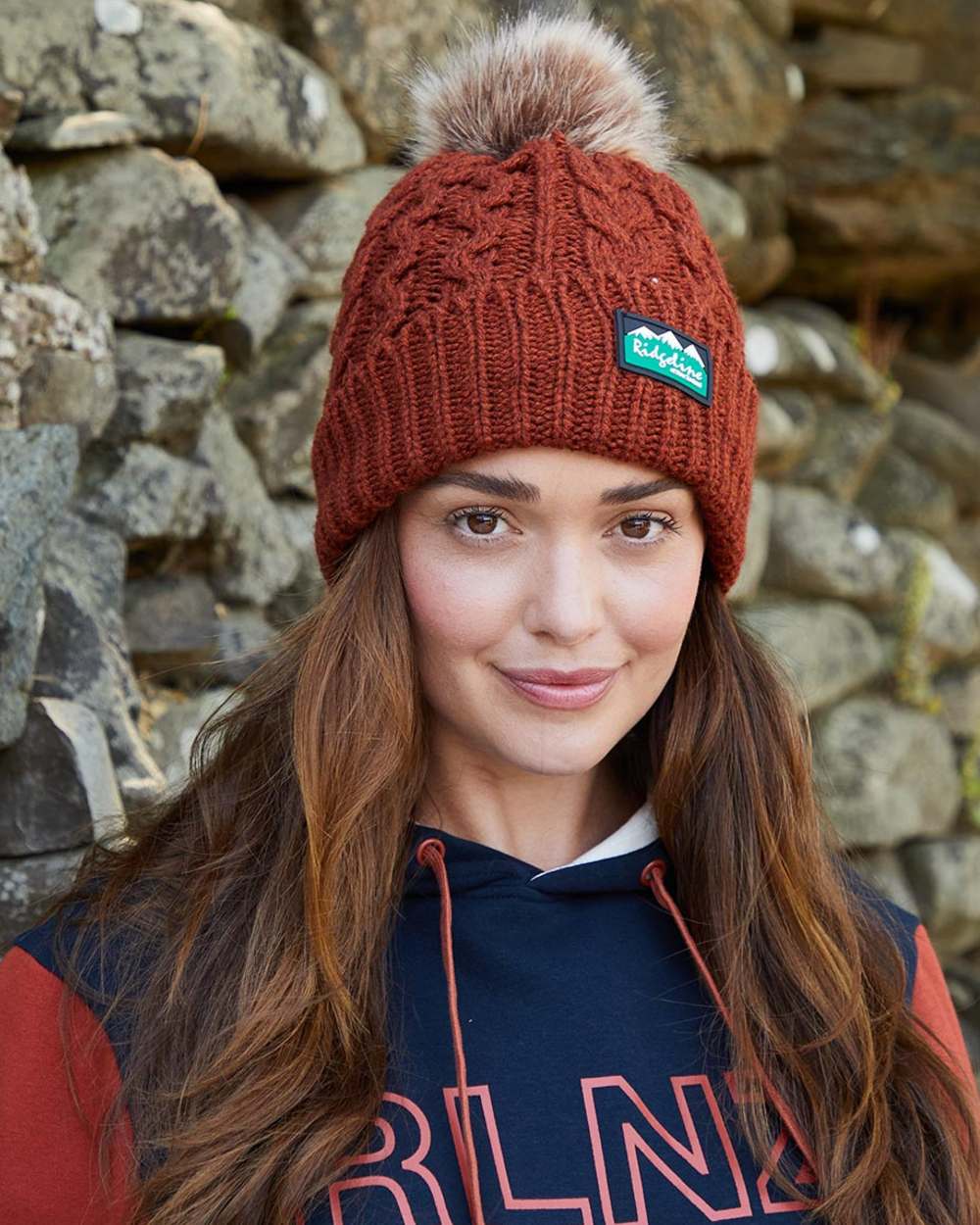 Russet coloured Ridgeline Nordic Fleck Bobble Hat on rock background #colour_russet