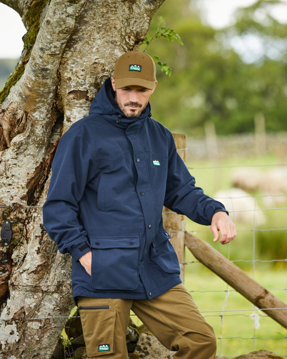 Navy coloured Ridgeline Torrent III Waterproof Jacket on blurry tree background #colour_navy