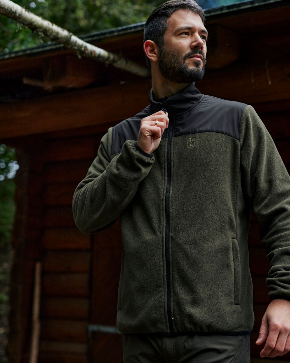 Rifle Green coloured Deerhunter Northward Fleece Jacket on Blurry Cabin background #colour_rifle-green