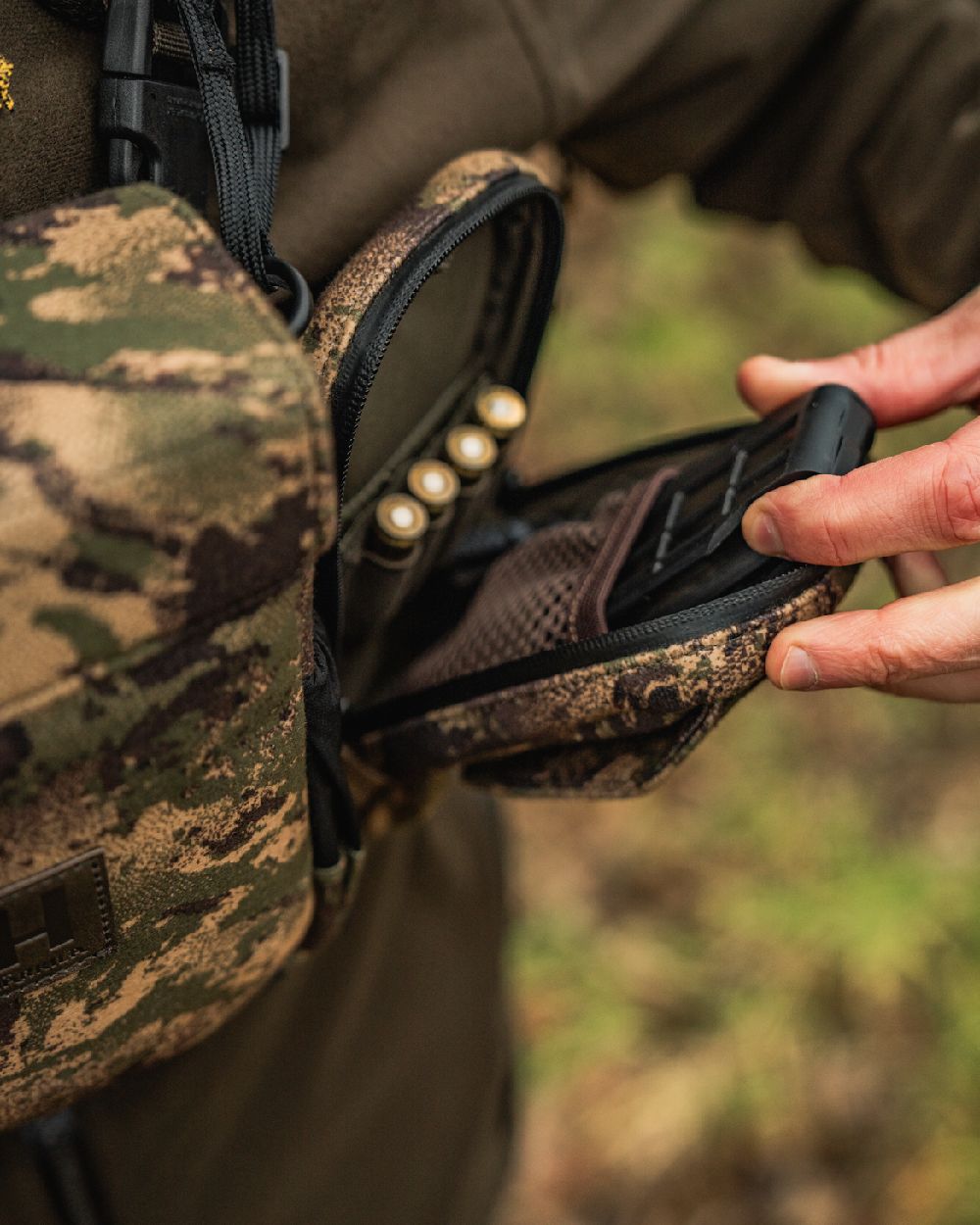 AXIS MSPForest Coloured Harkila Utility Camo Pouch on blurry background #colour_axis-mspforest