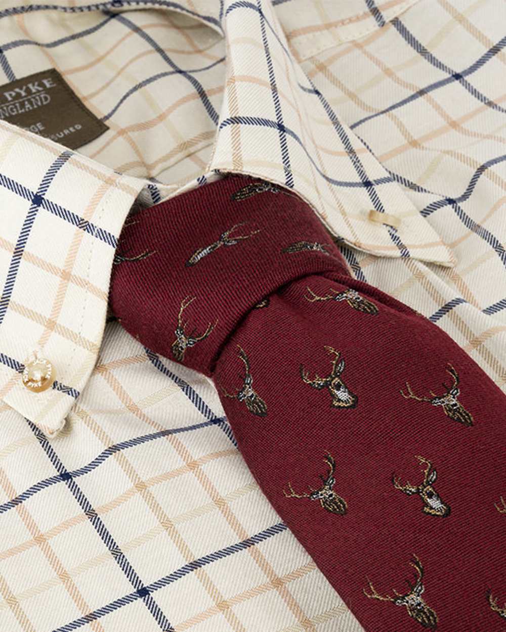 Burgundy coloured Jack Pyke Silk Tie Stag on shirt background #colour_burgundy
