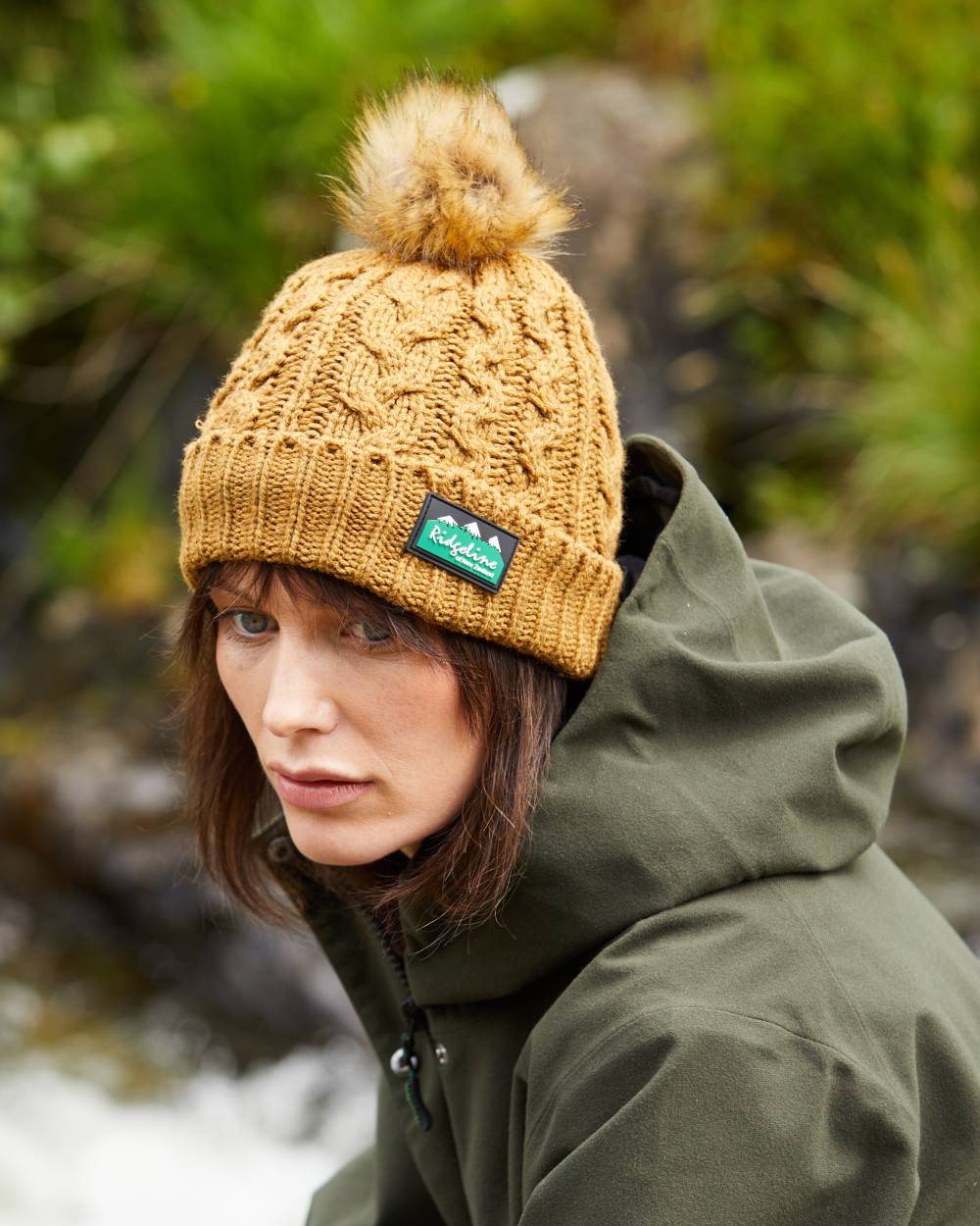 Ochre Coloured Ridgeline Nordic Fleck Bobble Hat On A Forest Background #colour_ochre