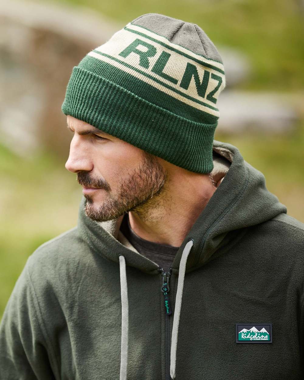 Olive Multi Coloured Ridgeline RLNZ Knitted Beanie On A Blurry Background #colour_olive-multi