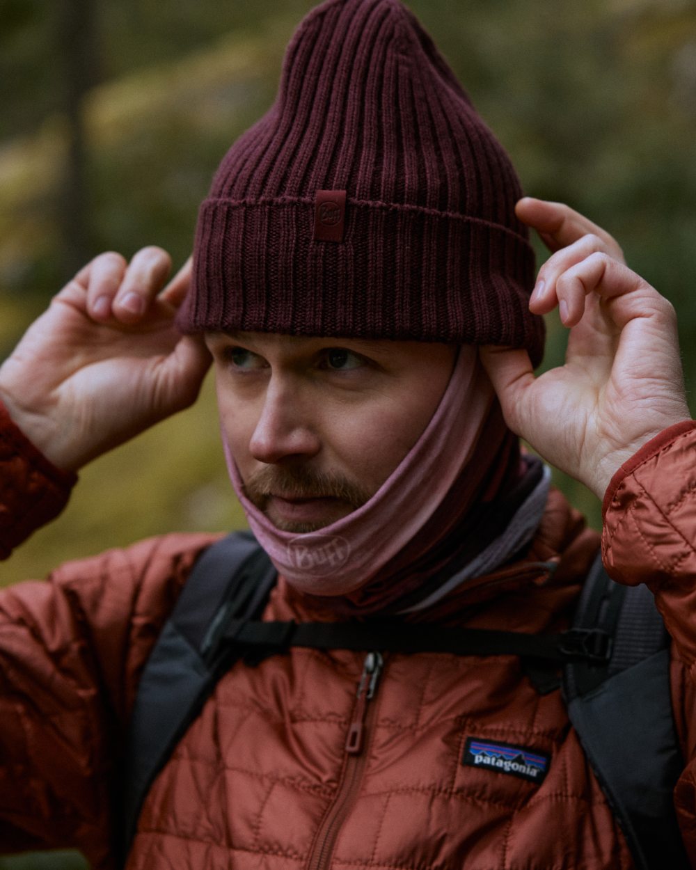 Maroon Coloured Buff Knitted Norval Beanie on blurry background #colour_maroon