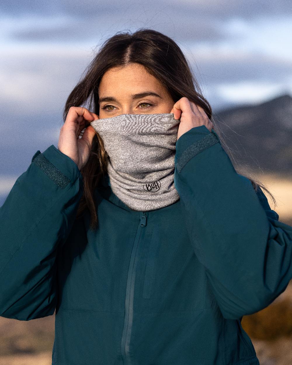 Light Grey Coloured Buff Merino Lightweight Neck Warmer on blurry background #colour_light-grey