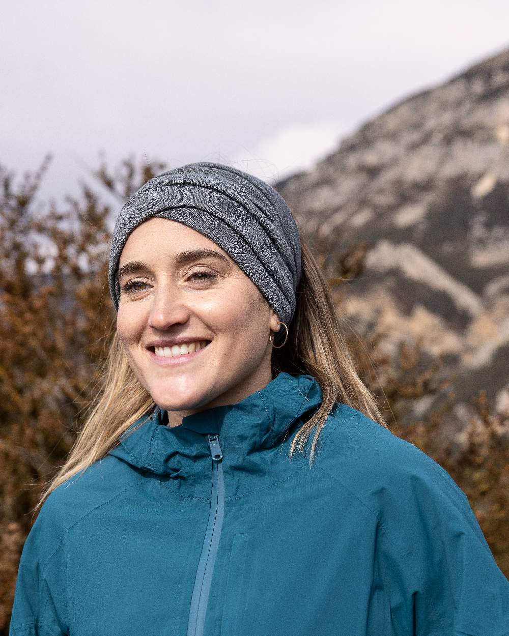 Light Grey Coloured Buff Merino Lightweight Neck Warmer on mountain background #colour_light-grey