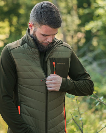 Forest Green coloured Deerhunter Chamois Padded Waistcoat on forest background #colour_forest-green