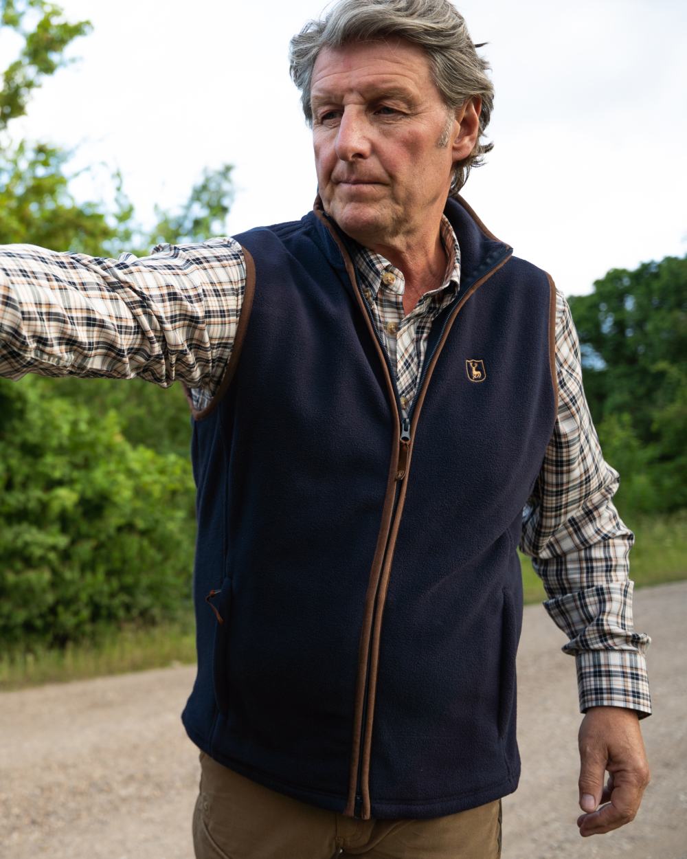 Dark Blue coloured Deerhunter Cumbria Fleece Waistcoat on forest background #colour_dark-blue