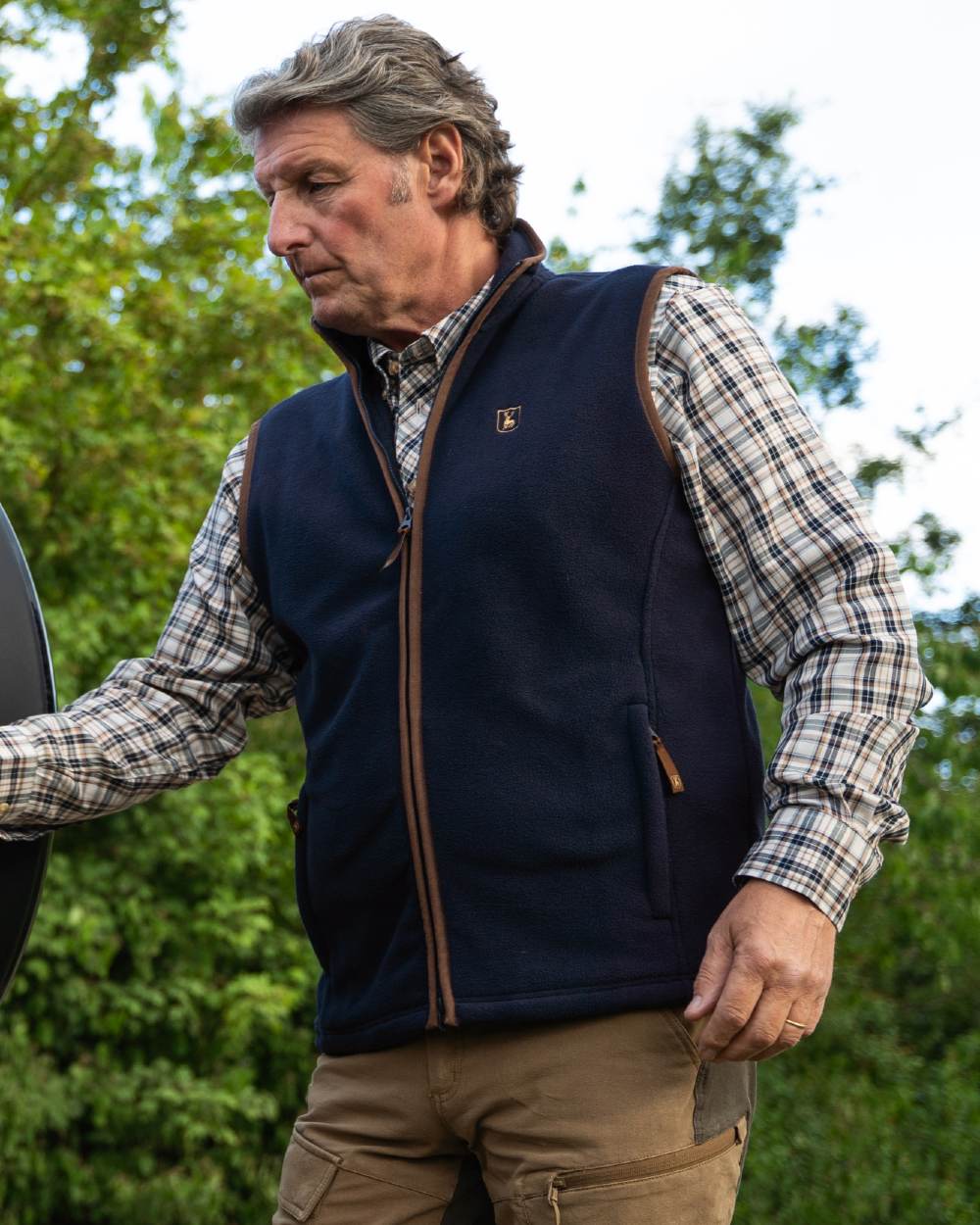 Dark Blue coloured Deerhunter Cumbria Fleece Waistcoat on forest background #colour_dark-blue