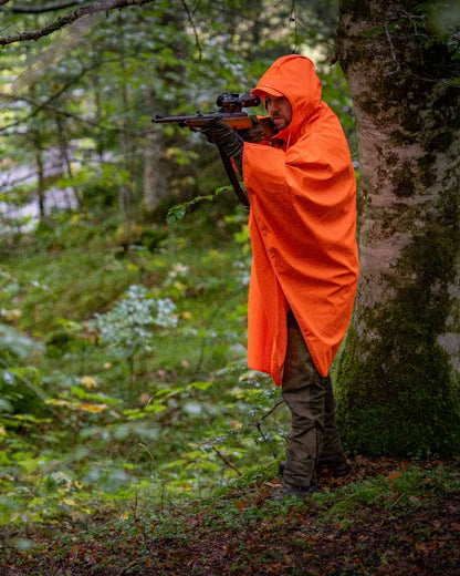 Orange coloured Deerhunter Hurricane Rain Poncho on forest background #colour_orange