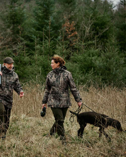 Peat coloured Deerhunter Lady Gabby Waterproof Boot Trousers on forest background #colour_peat