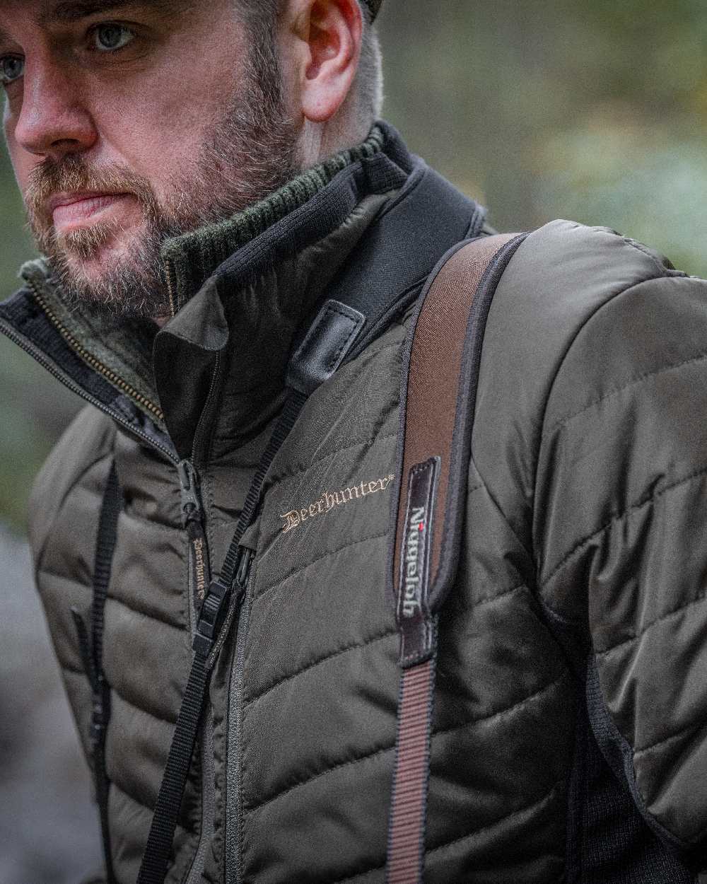 Adventure Green coloured Deerhunter Moor Padded Softshell Jacket on blurry background #colour_adventure-green