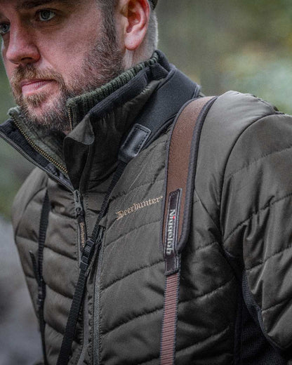 Adventure Green coloured Deerhunter Moor Padded Softshell Jacket on blurry background #colour_adventure-green