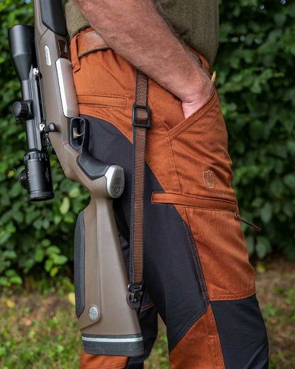 Burnt Orange Coloured Deerhunter Rogaland Contrast Stretch Trousers on forest background #colour_burnt-orange
