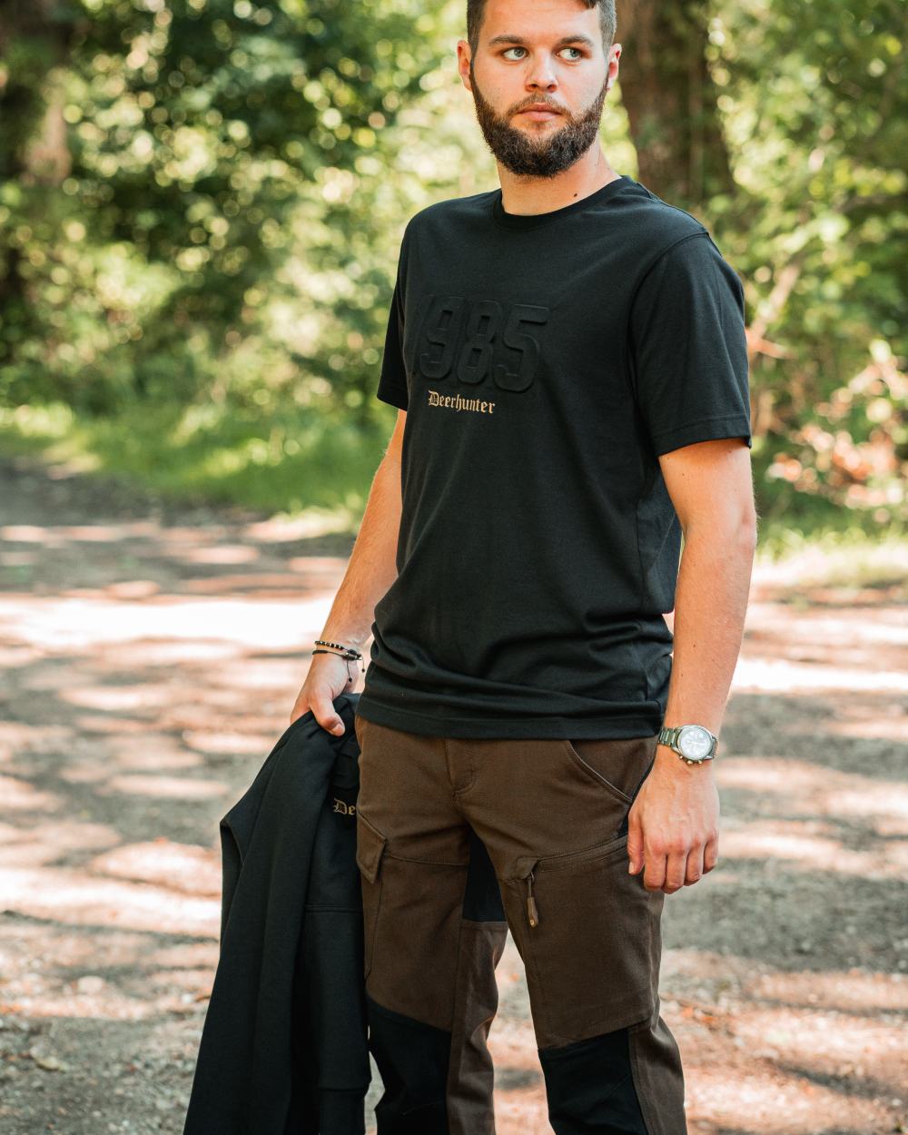 Fallen Leaf Black coloured Deerhunter Sarek Full Stretch Trousers on forest background #colour_fallen-leaf-black