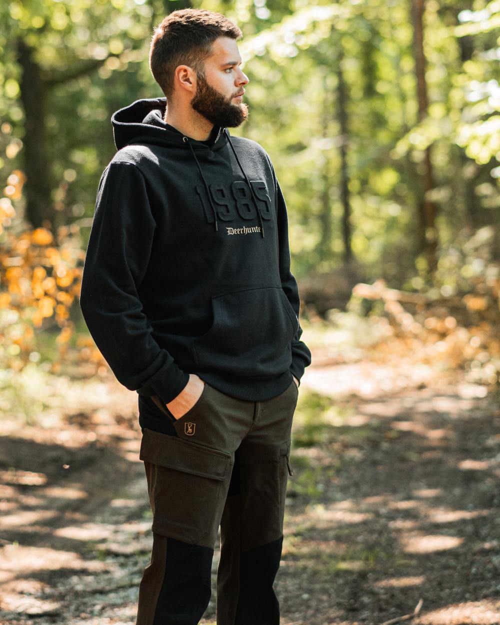 Fallen Leaf Black coloured Deerhunter Sarek Full Stretch Trousers on forest background #colour_fallen-leaf-black