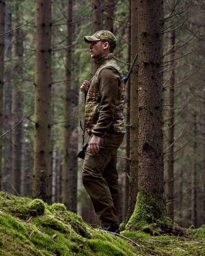 Willow Green AXIS Forest Coloured Harkila Deer Stalker Camo Reversible Packable Waistcoat on forest background #colour_willow-green-axis-forest