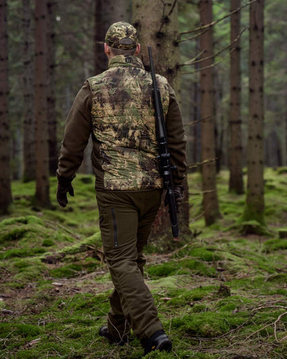 Willow Green AXIS Forest Coloured Harkila Deer Stalker Camo Reversible Packable Waistcoat on forest background #colour_willow-green-axis-forest