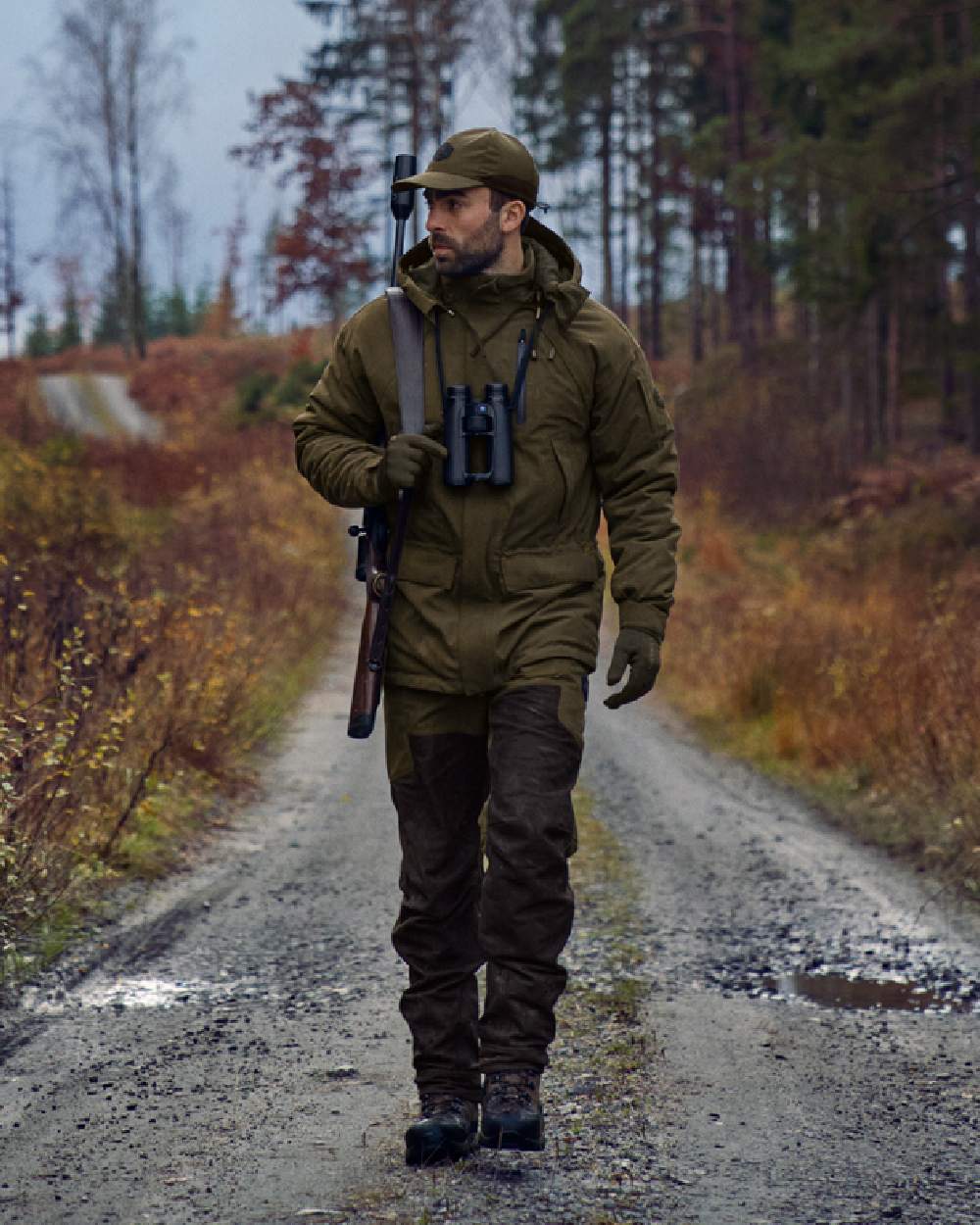 Willow Green Shadow Brown Coloured Harkila Driven Hunt HWS Leather Trousers on forest background #colour_willow-green-shadow-brown