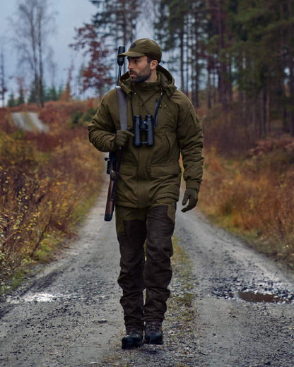 Willow Green Shadow Brown Coloured Harkila Driven Hunt HWS Leather Trousers on forest background #colour_willow-green-shadow-brown