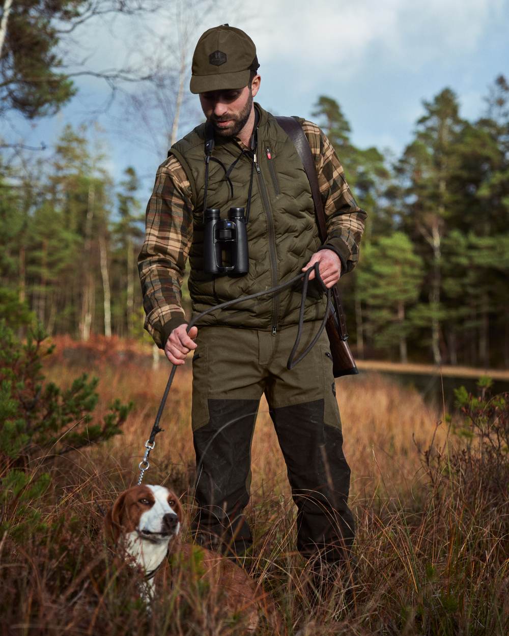 Willow Green Shadow Brown Coloured Harkila Driven Hunt HWS Leather Trousers on forest background #colour_willow-green-shadow-brown