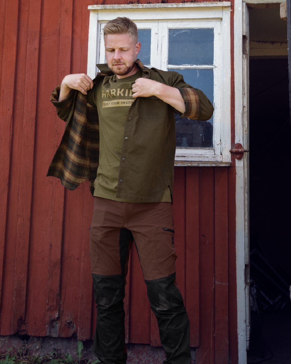 Dark Warm Olive Burgundy Coloured Harkila Eirik Reversible Shirt Jacket on countryside background #colour_dark-warm-olive-burgundy