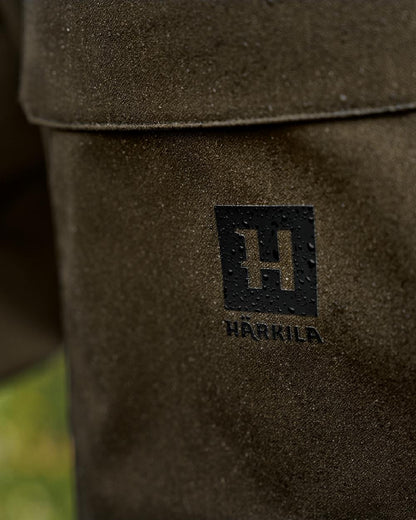 Hunting Green Coloured Harkila Finnmark HWS Trousers on blurry background #colour_hunting-green