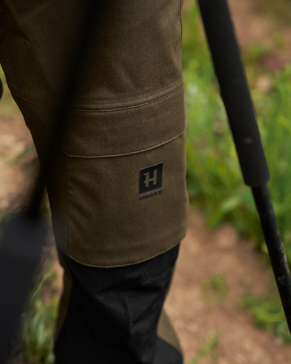 Hunting Green Coloured Harkila Finnmark HWS Trousers on blurry background #colour_hunting-green