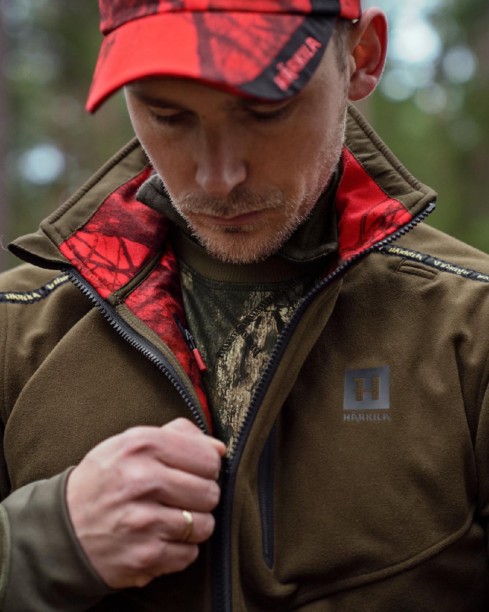 Hunting Green Mossy Oak Break-up Country Coloured Harkila Kamko Camo Reversible WSP Jacket on blurry background #colour_hunting-green-mossy-oak-break-up-country