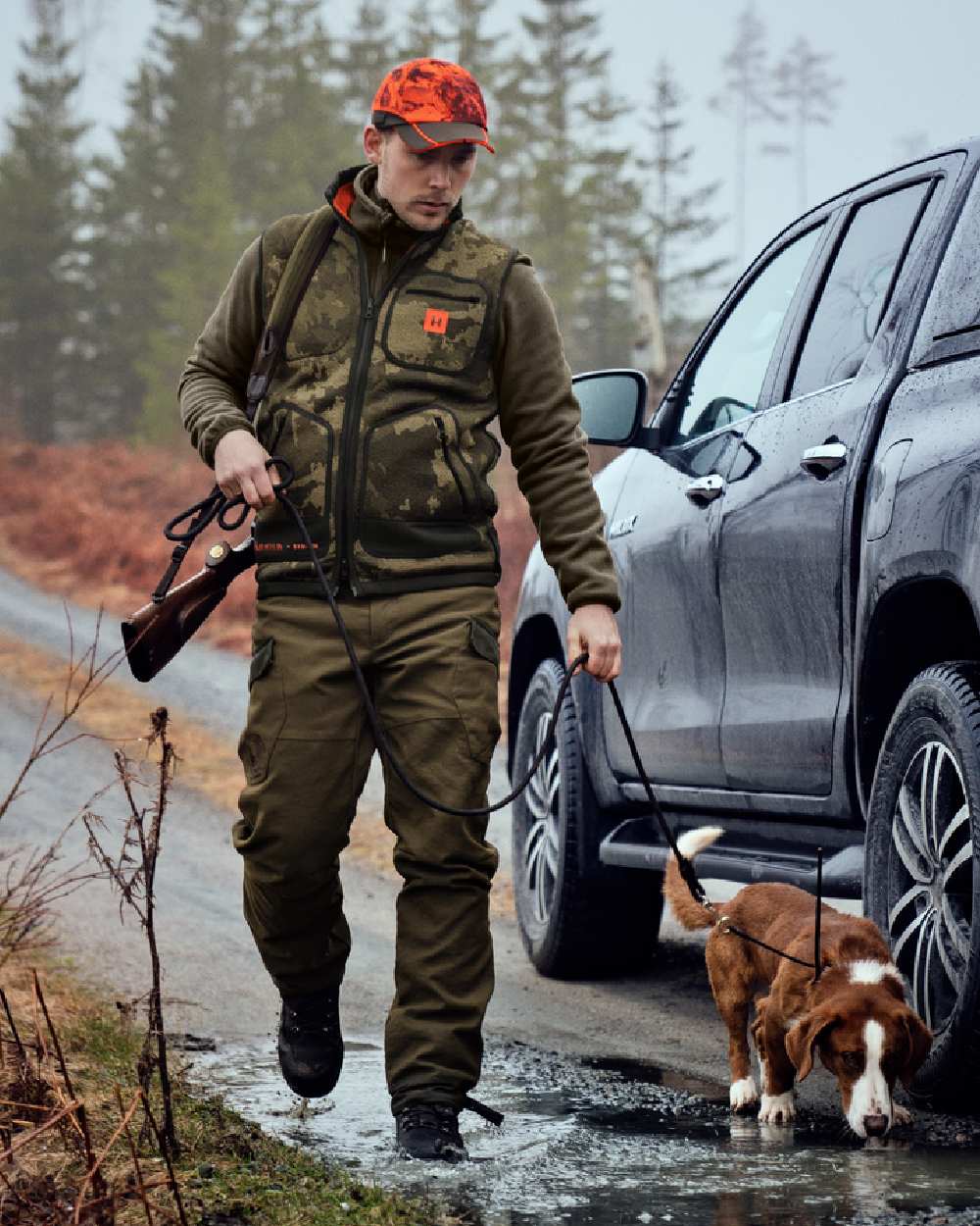 AXIS Limited Edition Orange Coloured Harkila Kamko Pro Edition Reversible Hi-Vis Waistcoat on forest background #colour_axis-limited-edition-orange