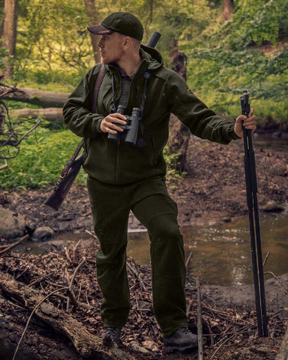 Willow Green Coloured Harkila Metso Hybrid Jacket on forest background #colour_willow-green