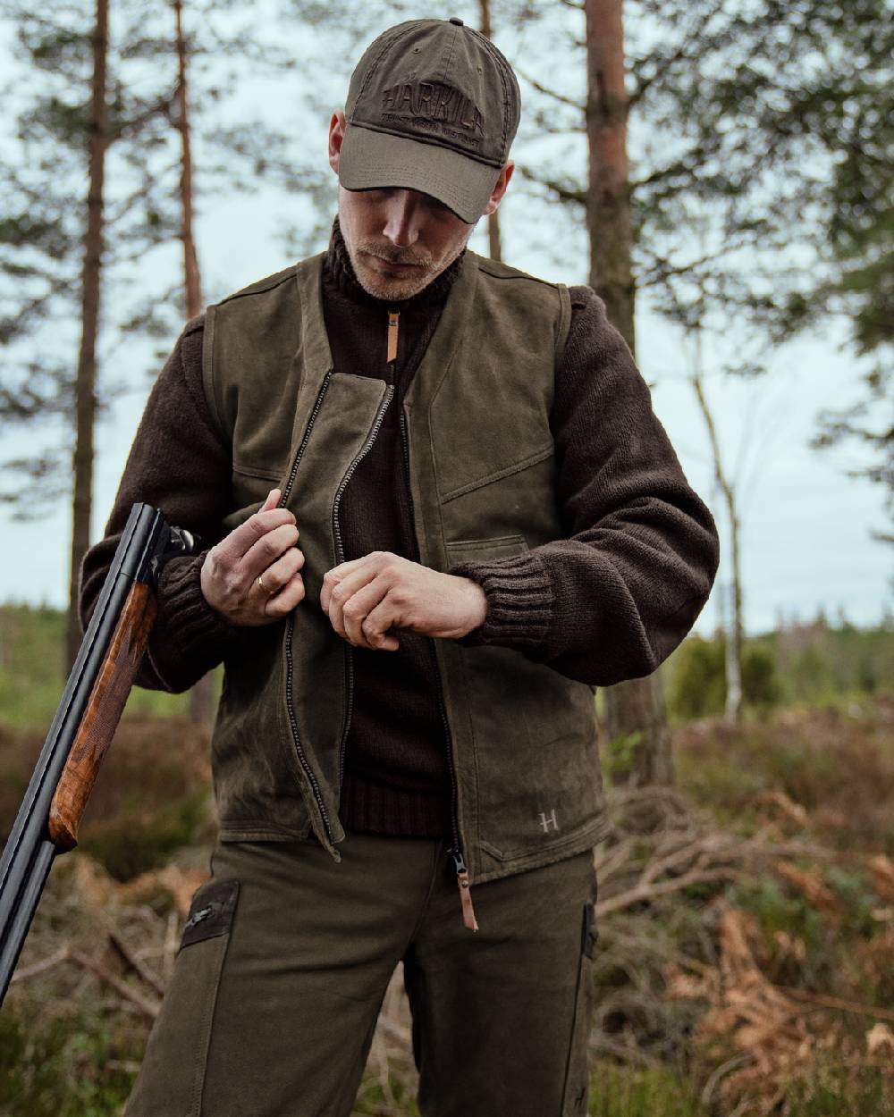 Willow Green Coloured Harkila Pro Hunter Leather Waistcoat on forest background #colour_willow-green