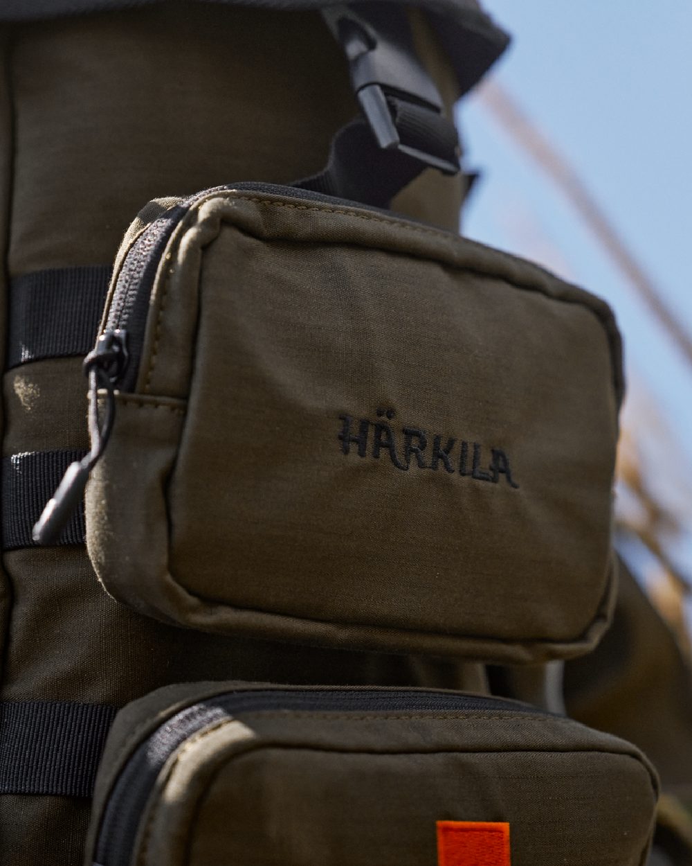 Willow Green Coloured Harkila Ragnar First Aid Backpack on blurry background #colour_willow-green