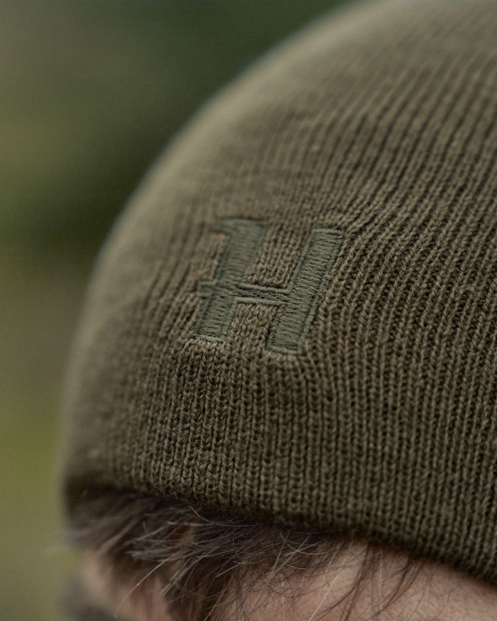 Willow Green Orange Coloured Harkila Reversible Beanie on outdoor background #colour_willow-green-orange