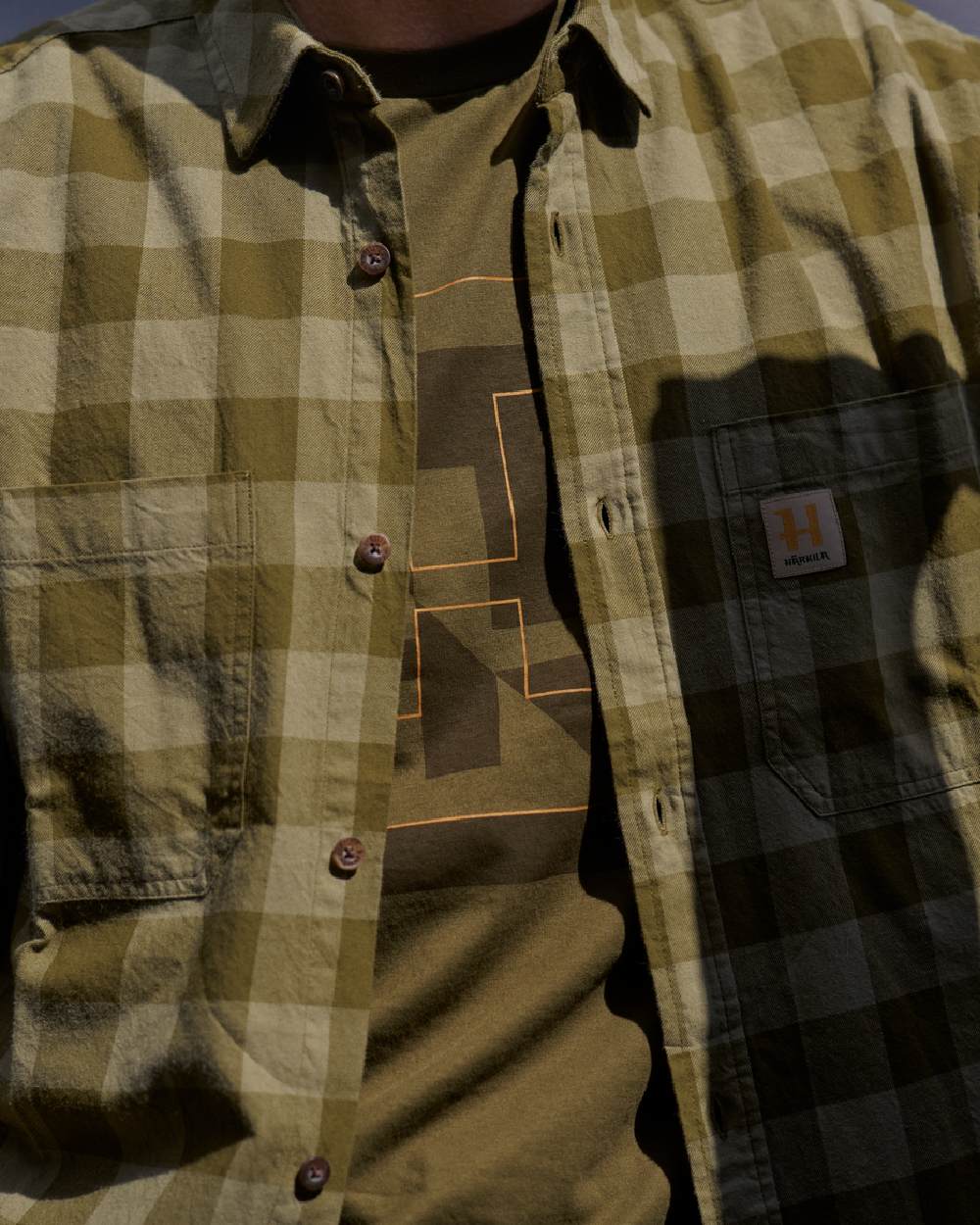 Dark Olive Check Coloured Harkila Scandinavian Long Sleeve Shirt on blurry background #colour_dark-olive-check