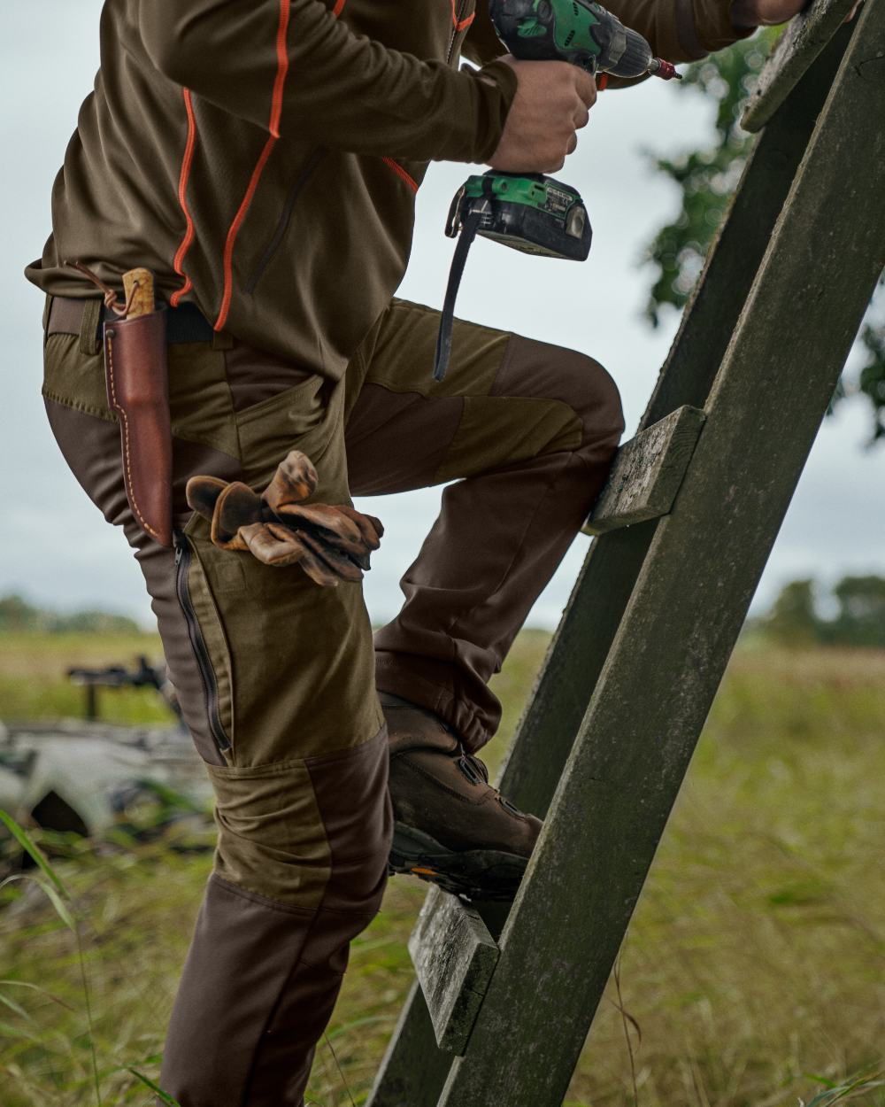 Willow Green Deep Brown Coloured Harkila Scandinavian Trousers on forest background #colour_willow-green-deep-brown