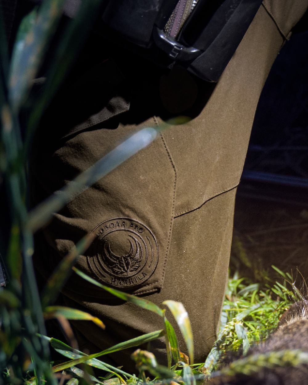 Willow Green Coloured Harkila Wildboar Pro Move Trousers on outdoor background #colour_willow-green